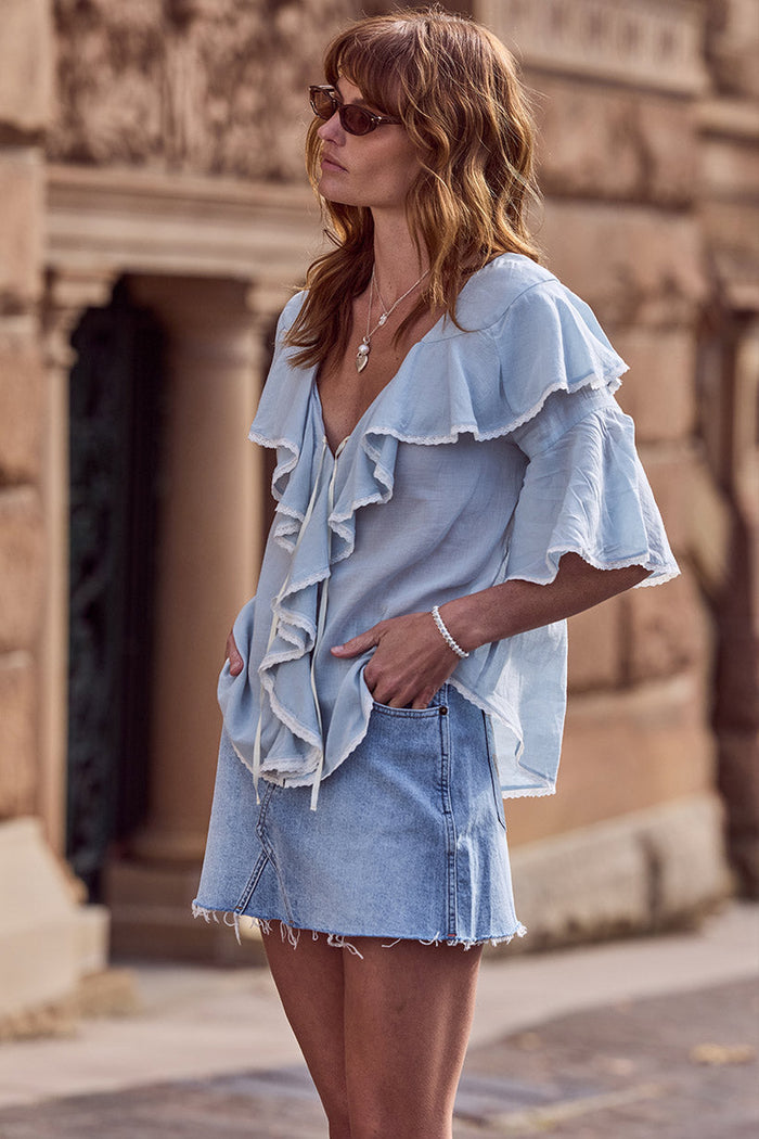 Model wearing vintage blue organic cotton denim mini skirt, side view showing frayed hem and low waist