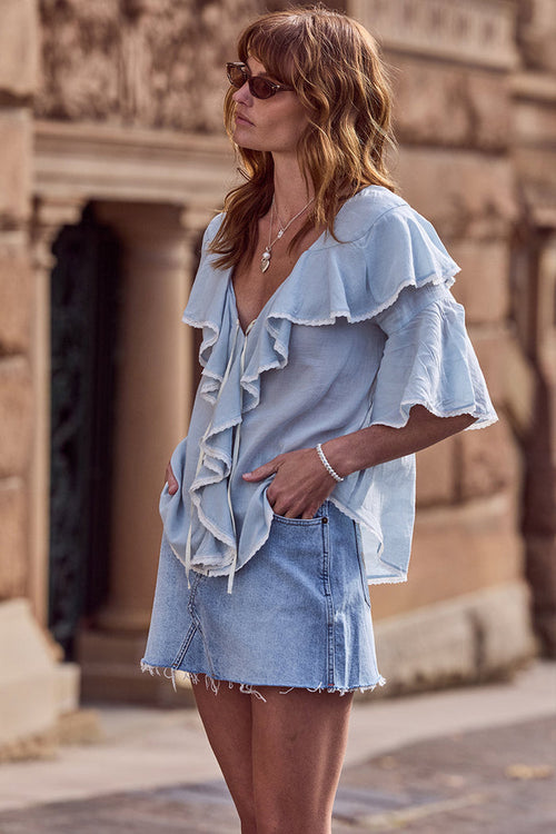 Model wearing vintage blue organic cotton denim mini skirt, side view showing frayed hem and low waist