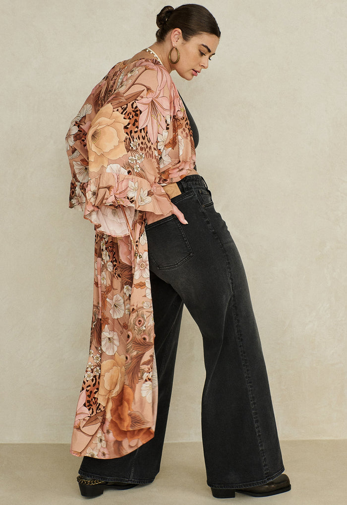 Side view: a model wearing vintage black organic cotton relaxed jeans with floral print kimono, mid-rise 5-pocket style