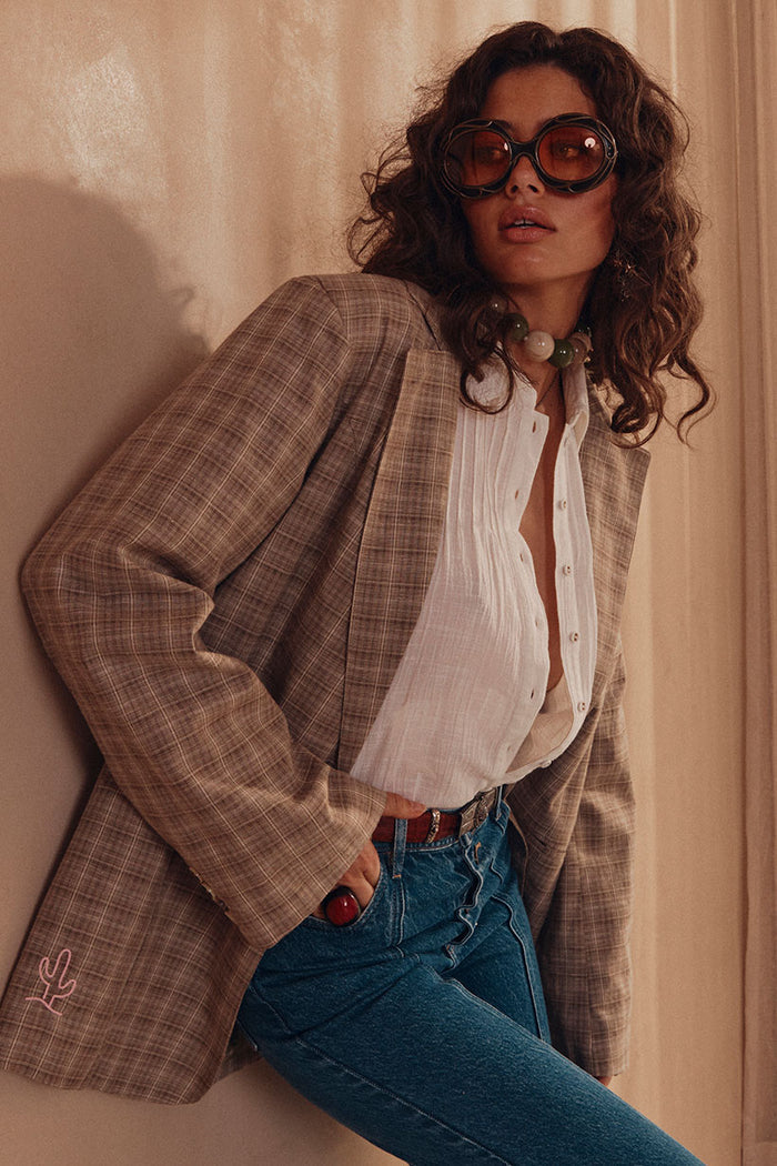 Front view of grey check oversized blazer with wide shoulders, custom embroidery, styled open over white shirt with jeans