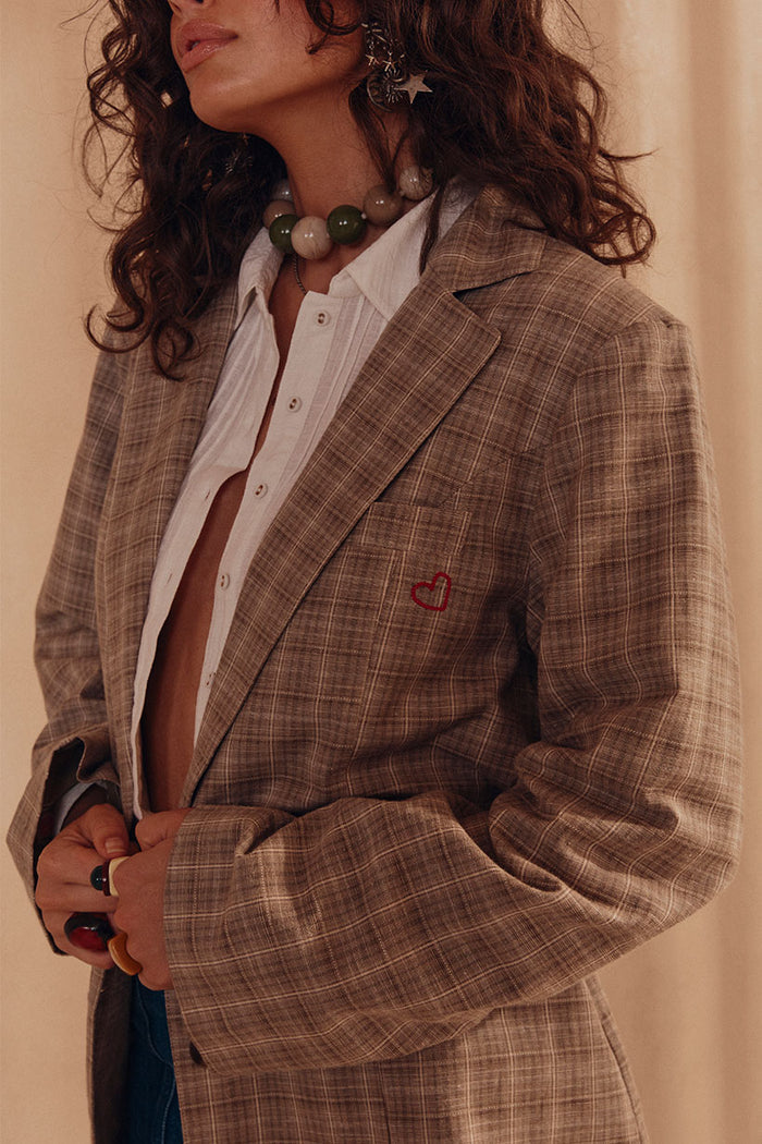 Close-up of check blazer chest welt pocket with red heart embroidery detail, notched lapel visible
