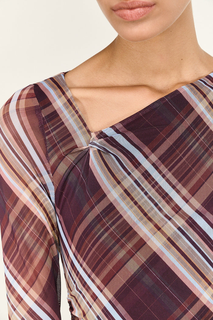 Plaid patterned top worn by a person on a neutral background