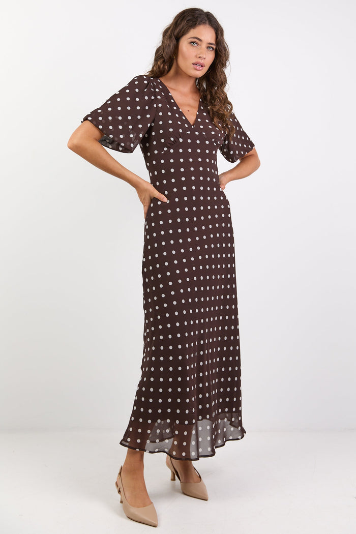 Woman wearing a brown dress with white polka dots on a white background