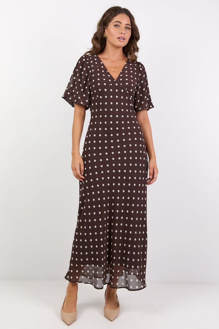 Woman wearing a brown dress with white patterns on a white background