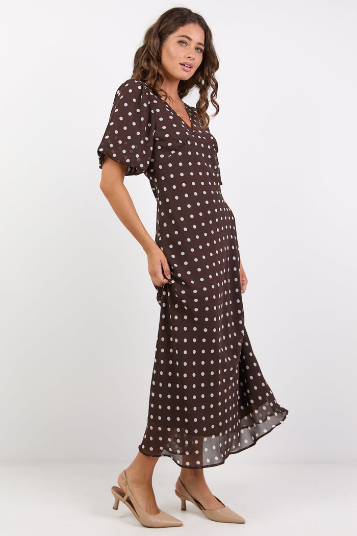 Woman wearing a brown polka dot dress on a white background