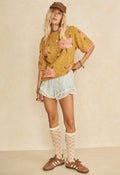Model wearing mustard Coastal Granny Top, full-length front view styled with ruffled shorts and lace knee-high socks