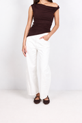 A woman modeling a dark brown off-the-shoulder knit top and white wide-leg pants against a clean white studio background.