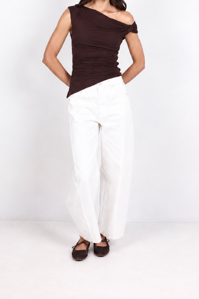 A woman modeling a dark brown off-the-shoulder ribbed top and white wide-leg pants against a plain white studio background.