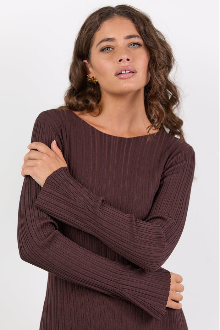Woman wearing a brown ribbed dress against a white background