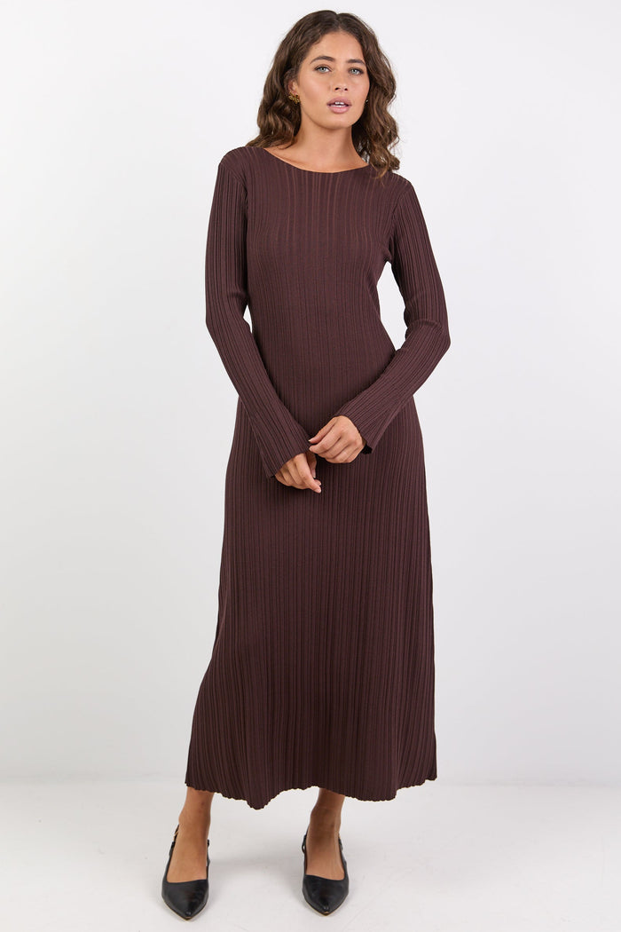 Woman wearing a long brown ribbed dress on a white background