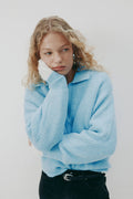 Woman wearing a light blue sweater against a white background