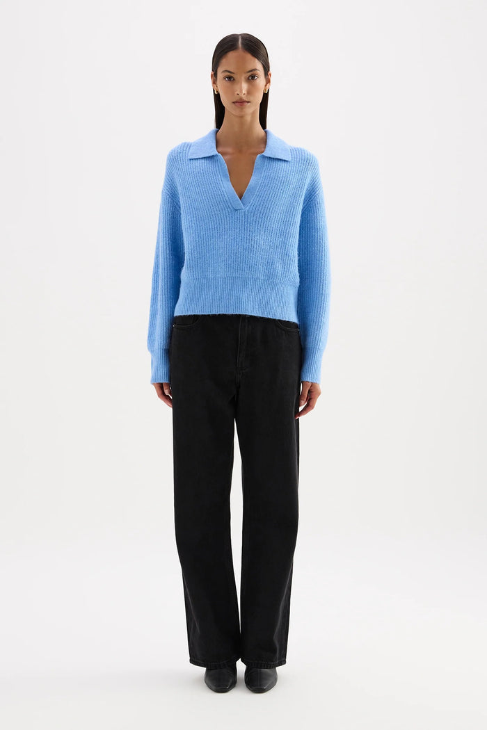 Woman wearing a light blue sweater and black pants on a white background
