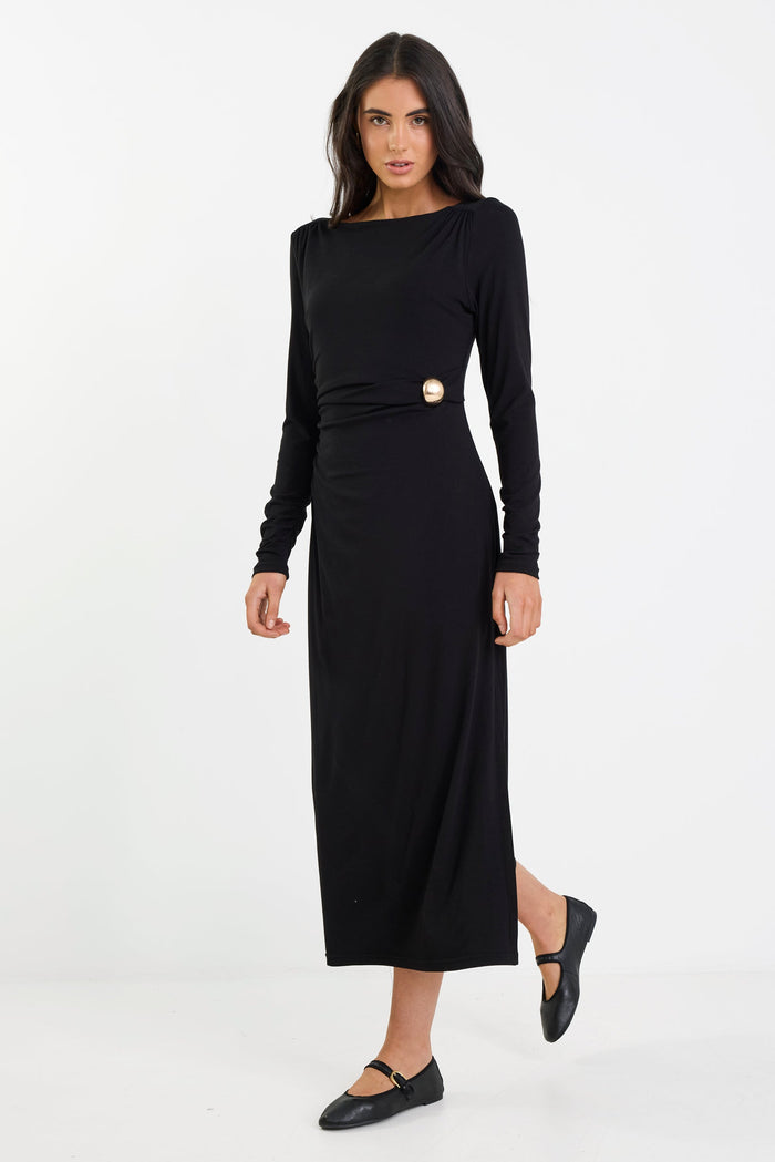 Woman wearing a black dress with a gold button on a white background