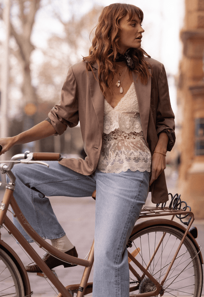 Dallas Blazer in Smokey Taupe styled with white lace cami and light-wash jeans, side view on model beside bicycle