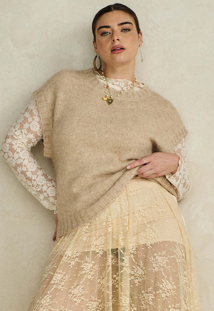 Model wearing Darcy Vest in sand, front view, styled over floral lace with rib neckband and hemband detail