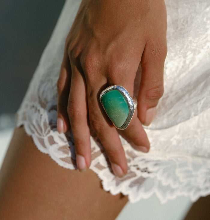 Close-up of large green chrysoprase stone in hammered sterling silver-plated setting, worn on middle finger