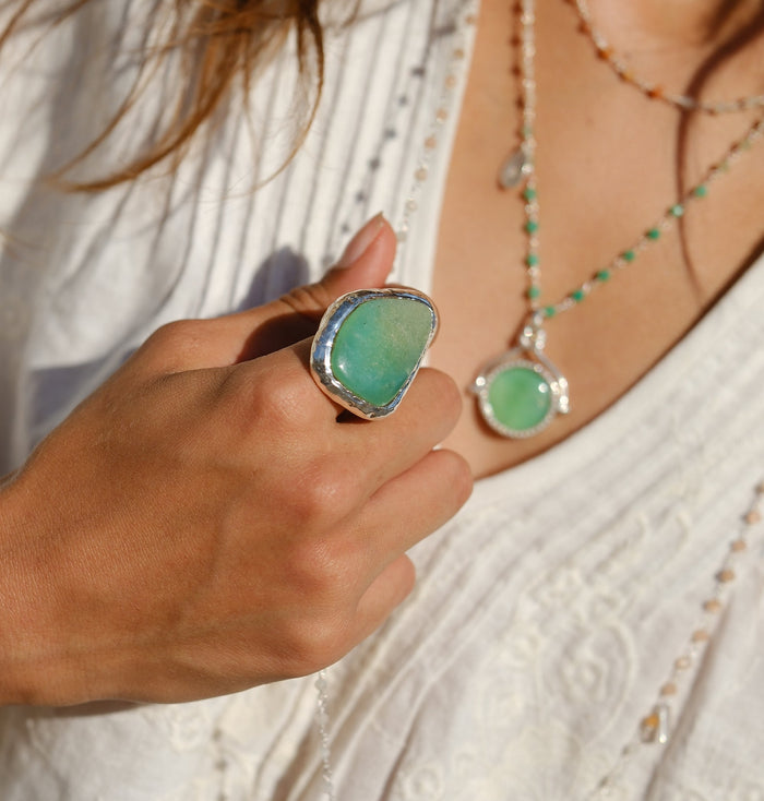 Close-up of large organic green chrysoprase stone in hammered silver-plated brass setting worn on finger
