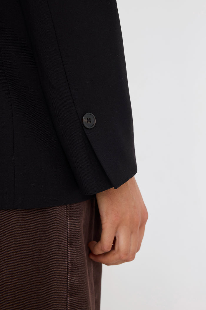 Close-up of a black suit jacket with a button on a white background