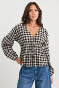 Woman wearing a black and white checkered blouse with blue jeans on a white background
