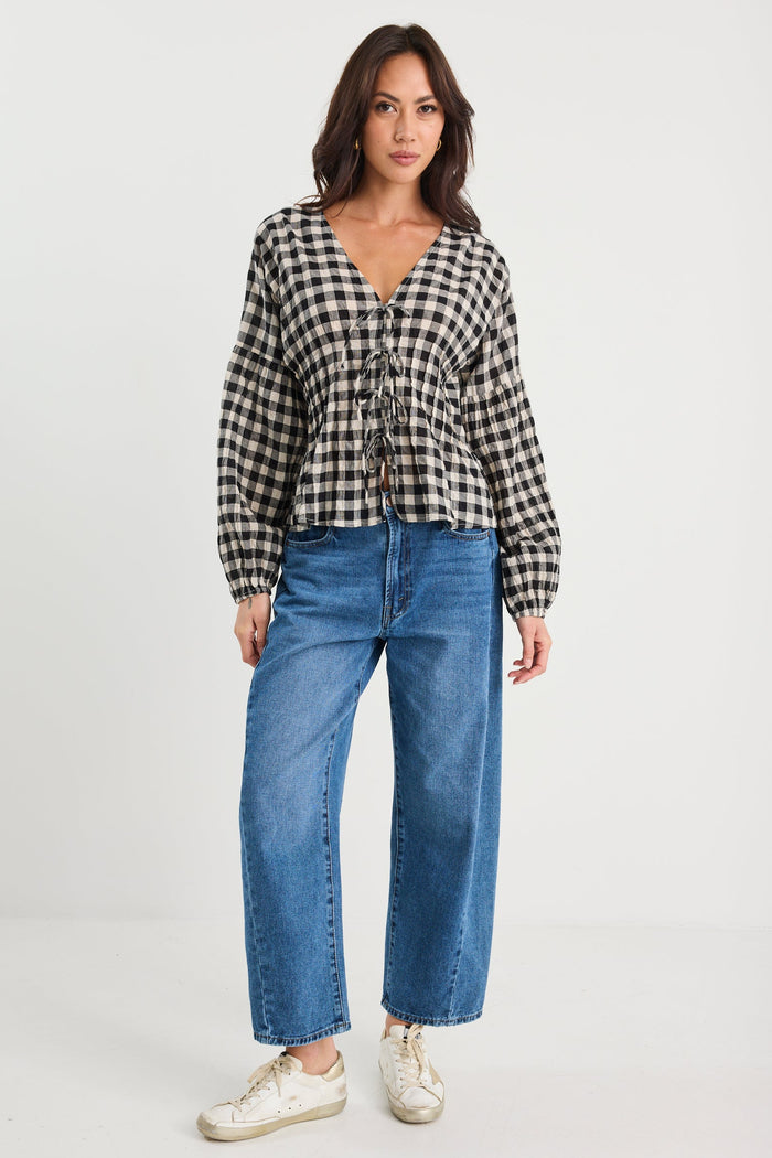 Woman wearing a checkered shirt and blue jeans on a white background