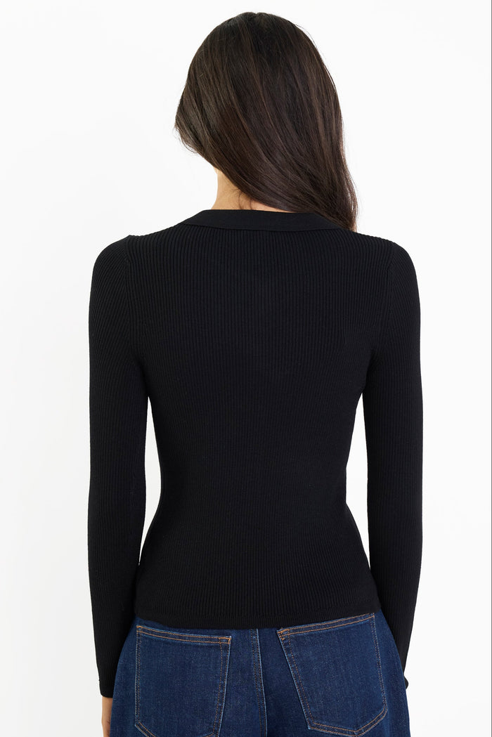 Person wearing a black long-sleeve top and blue jeans on a white background