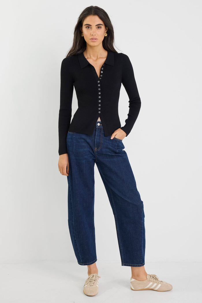 Woman wearing a black cardigan and blue jeans on a white background