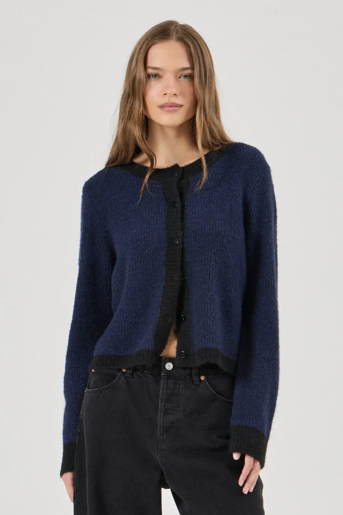 Woman wearing a blue cardigan over a black shirt and pants on a white background