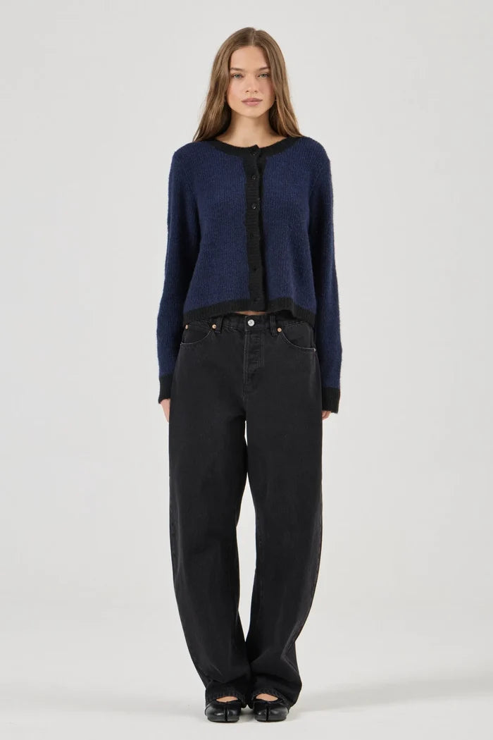 Woman wearing a blue cardigan and black pants on a white background