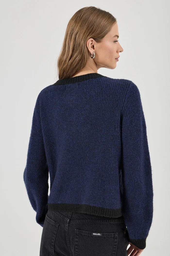 Woman wearing a blue sweater with black trim on a white background
