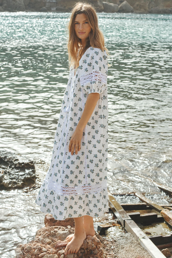 Side view of lace-insert midi dress with raglan sleeves, tassel ties, and floral block print, worn at waterside
