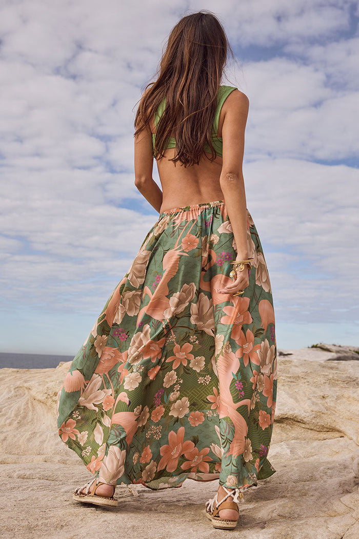Back view of Floridian Maxi Skirt in Sage, showing elastic waist and full-length floral print on rocky outdoor surface