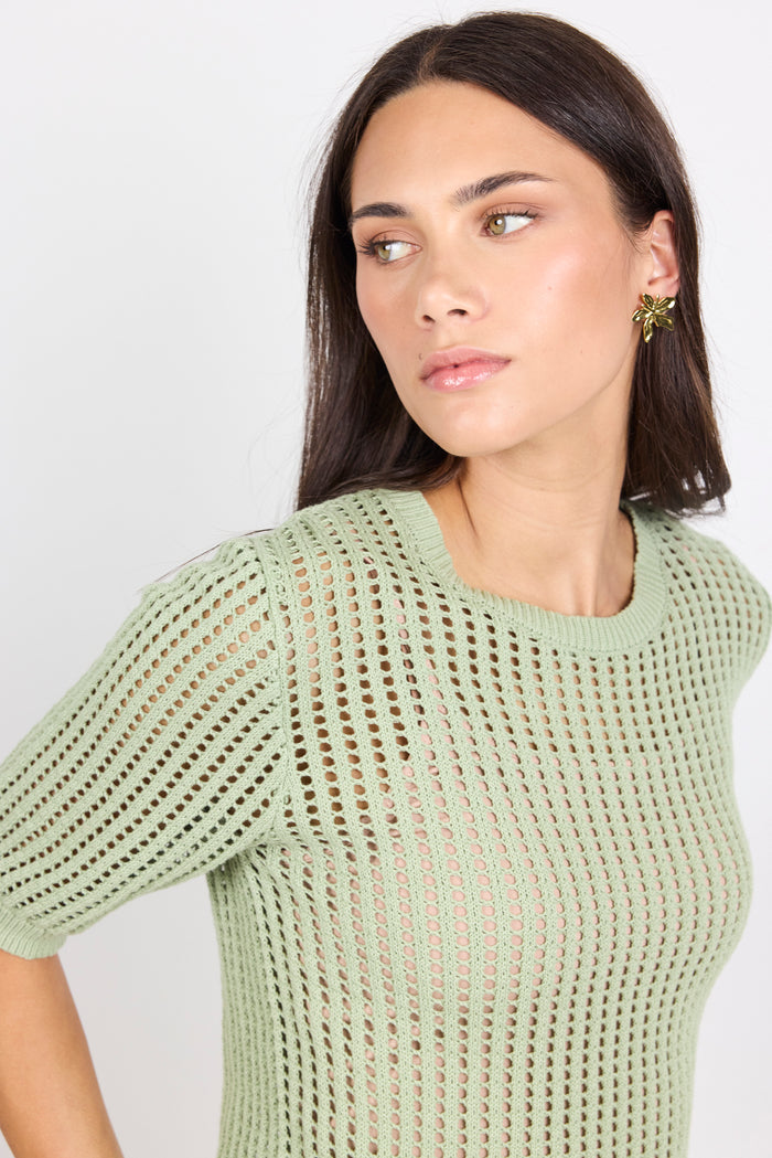 Woman wearing green knit tee and blue denim jeans on white background.