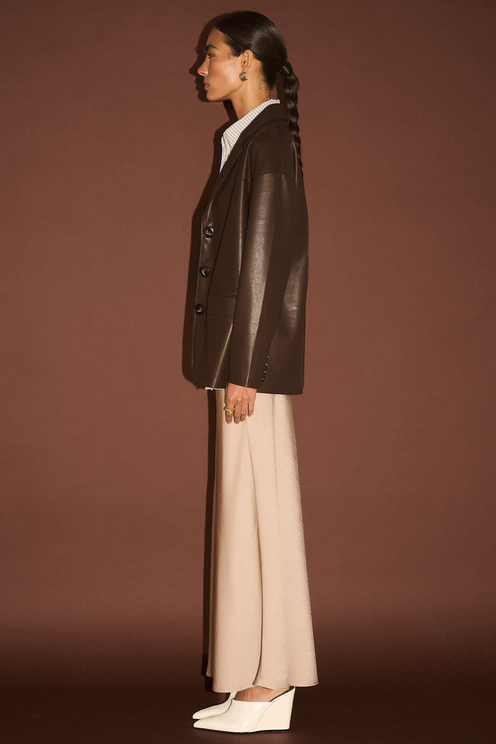 Person wearing a brown leather jacket and beige pants against a brown background
col_pattern