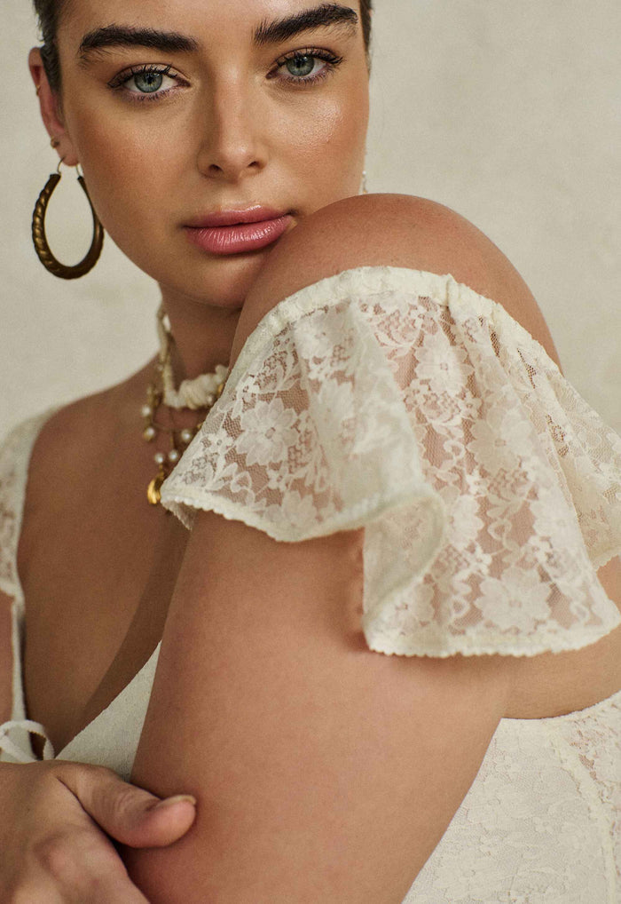 Close-up of flutter lace shoulder strap detail on Glastonbury Lace Dress in antique white