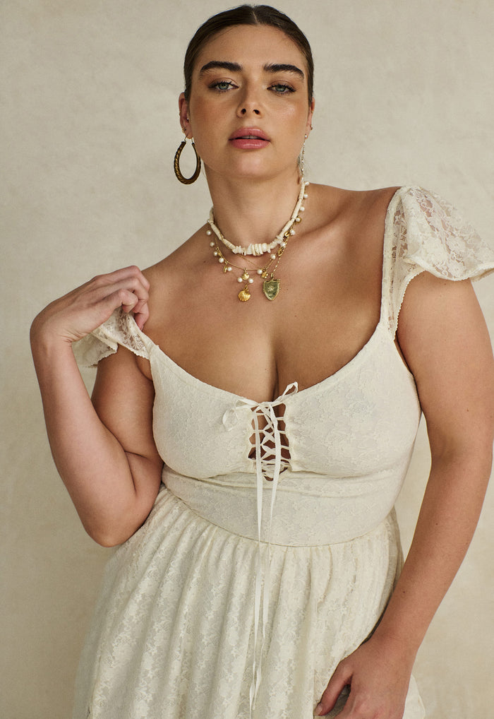 Close-up of Glastonbury Lace Dress bodice showing front lace-up detail and flutter shoulder straps in antique white