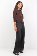 Woman wearing a brown button-up shirt and black wide-leg pants on a white background