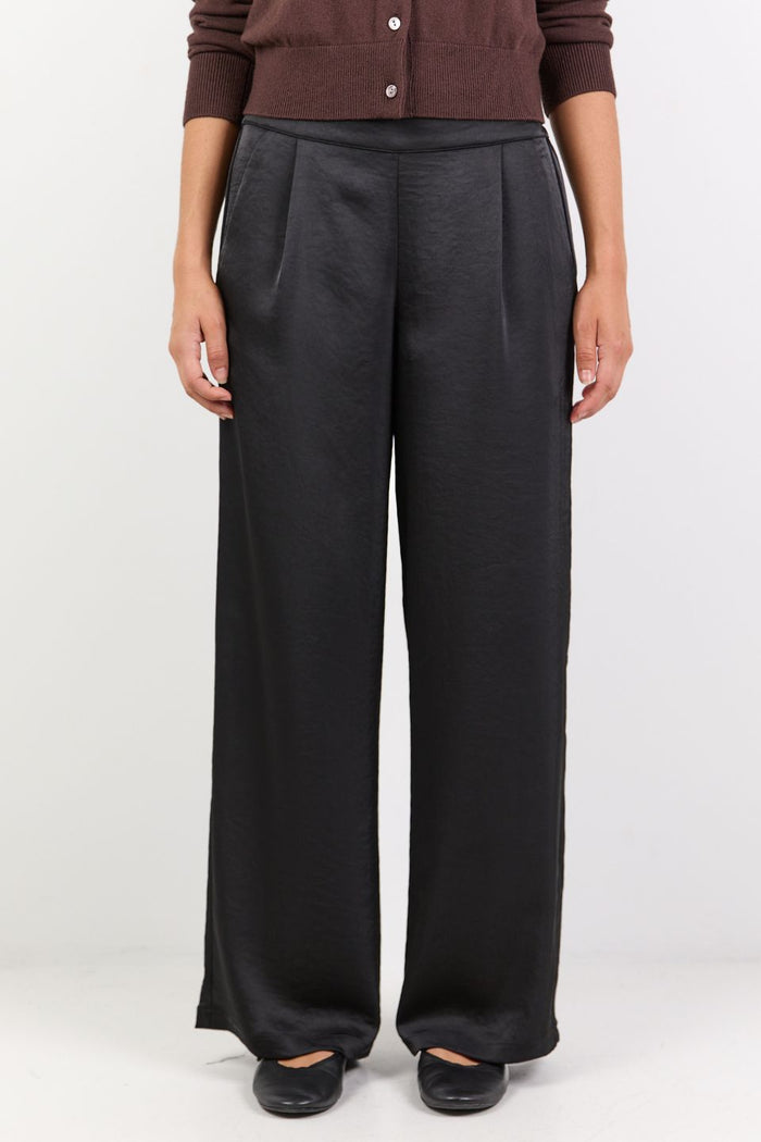 Person wearing dark gray wide-leg pants on a white background