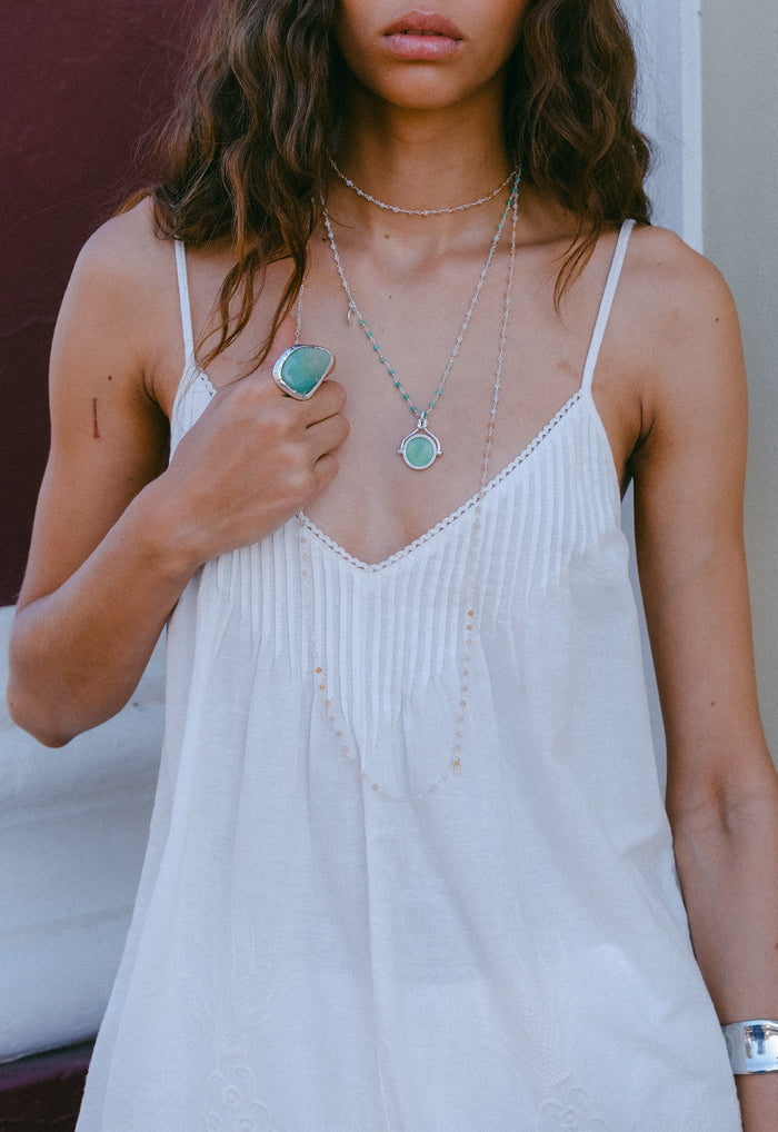Front detail of white organic cotton-linen cami showing V-neck with embroidery trim and pintuck bust styling