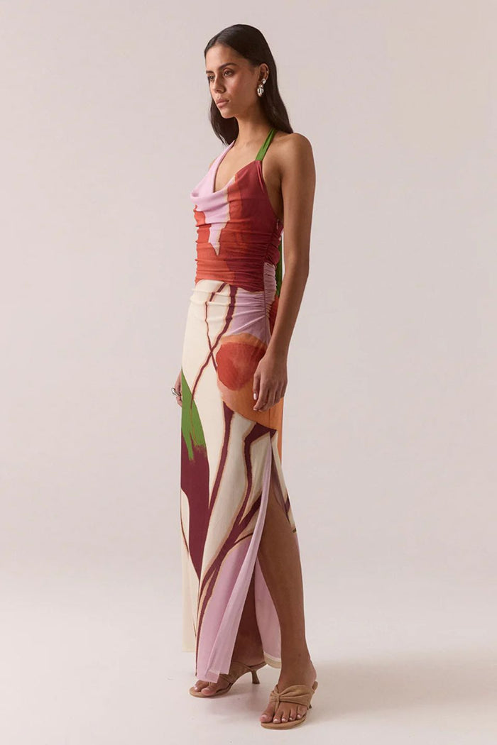 Woman wearing a colorful dress with a pattern on a plain background