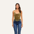 A woman wearing the Kalea Velvet Bodysuit in gold, featuring a scoop neckline, paired with blue jeans and a wide belt, along with a bracelet, stands facing forward against a plain light background.