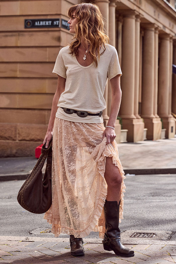 Model styled in lace maxi skirt with hi-lo hem, ruffle lace trim, side tie waist, paired with boots on city street