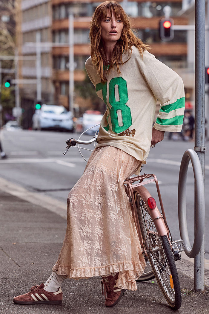 Model styled in lace maxi skirt with ruffle hem trim and slip lining, leaning against bicycle on city street
