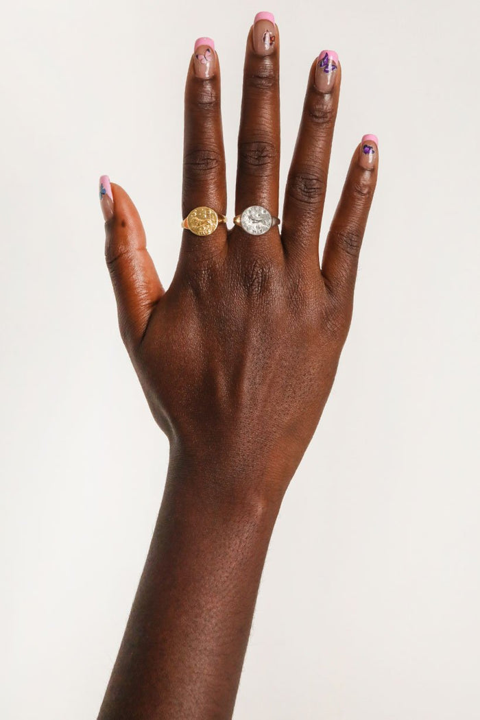Close up image of a hand with painted nails wearing gold rings, including that of the Spell’s Stargazer Zodiac Ring.