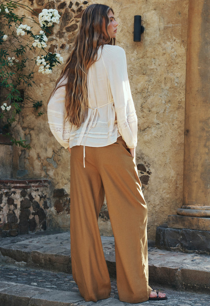 Model wearing London Pleated Pant in Tan, back view showing adjustable buckle waist and relaxed wide leg