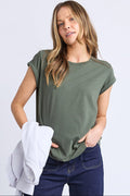 Woman wearing a green scoop neck tee and dark blue jeans