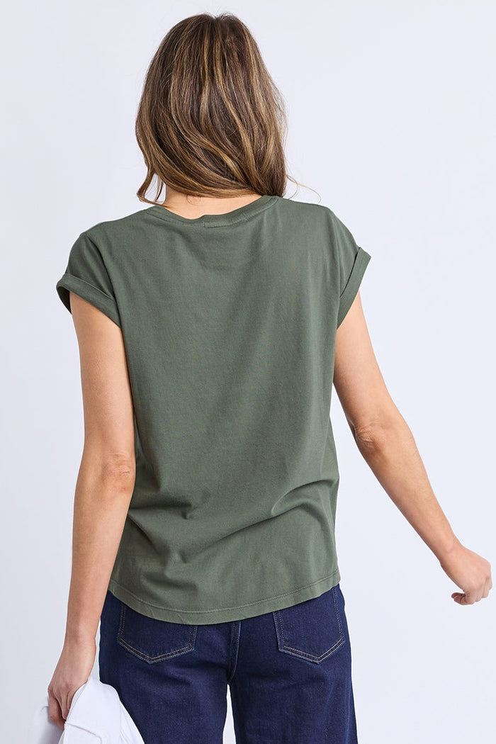 Woman wearing a green scoop neck tee and dark blue jeans