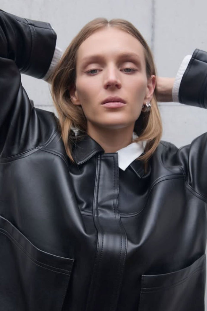 Person wearing a black leather jacket with a plain background