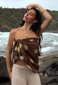 Spell Melo x Spell Travel Scarf in Melo Brown Modal with golden sun print, worn as strapless top at beach