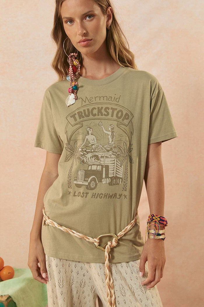Front view of khaki slub cotton Mermaid Truckstop Biker Tee with mermaid graphic print, styled with braided belt