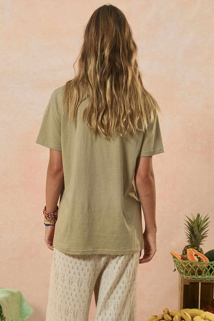 Back view of khaki slub cotton biker tee showing relaxed fit and short sleeves, styled with white lace pants